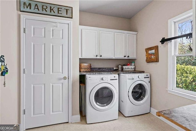 washroom featuring washing machine and dryer, cabinets, and a healthy amount of sunlight