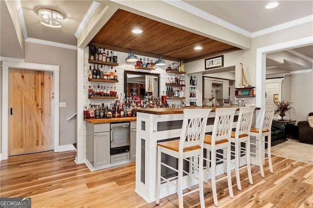 bar with ornamental molding, wooden counters, wooden ceiling, and light wood-type flooring