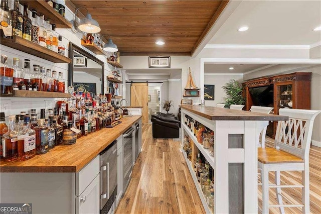 bar with crown molding, wooden counters, light hardwood / wood-style floors, wooden ceiling, and a barn door