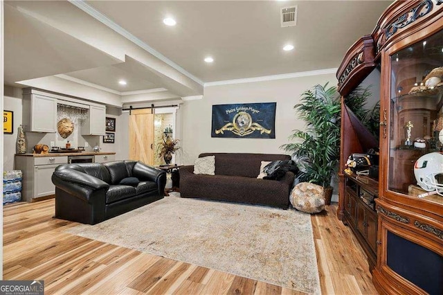 living room featuring crown molding, a barn door, and light hardwood / wood-style flooring