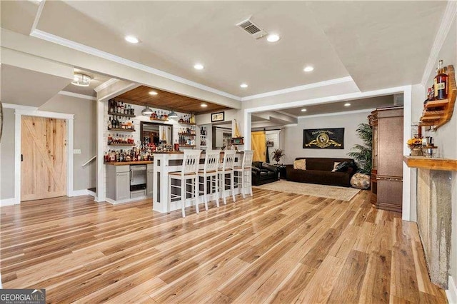 interior space with ornamental molding, bar area, and light wood-type flooring