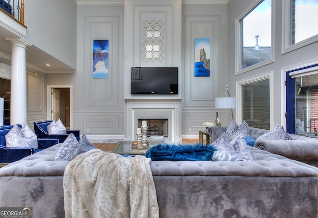 living room with ornate columns, ornamental molding, and a high ceiling