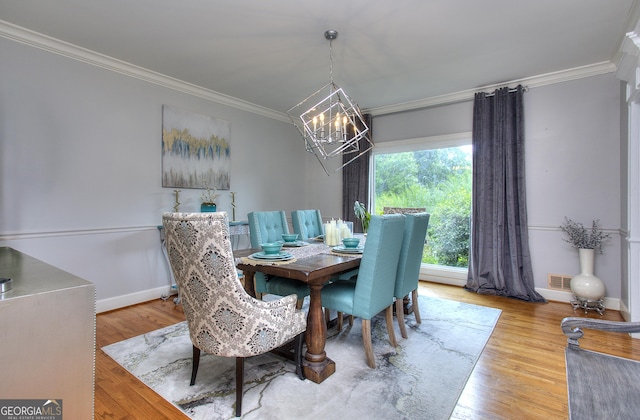 dining room with an inviting chandelier, crown molding, and hardwood / wood-style floors