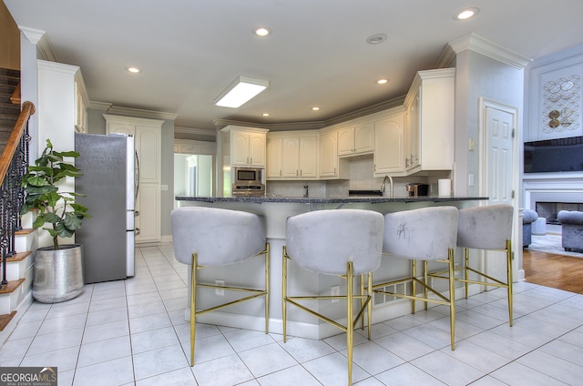 kitchen with crown molding, a breakfast bar area, appliances with stainless steel finishes, backsplash, and kitchen peninsula