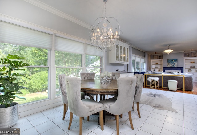 dining room with built in shelves, ornamental molding, a chandelier, and light tile patterned floors