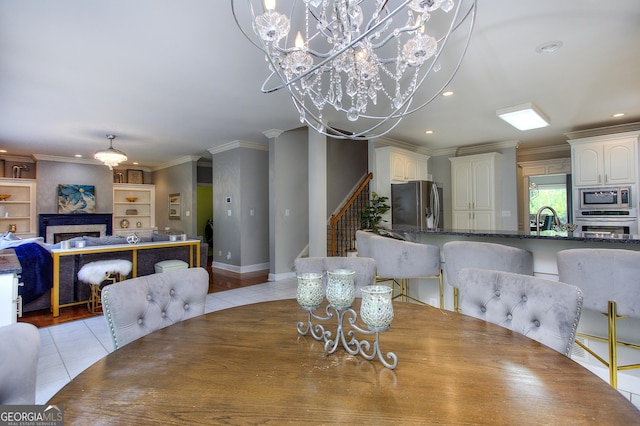 tiled dining room with built in shelves, ornamental molding, a chandelier, and sink