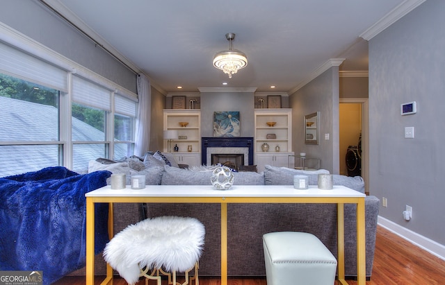 living room featuring crown molding, washer / dryer, hardwood / wood-style floors, and built in features