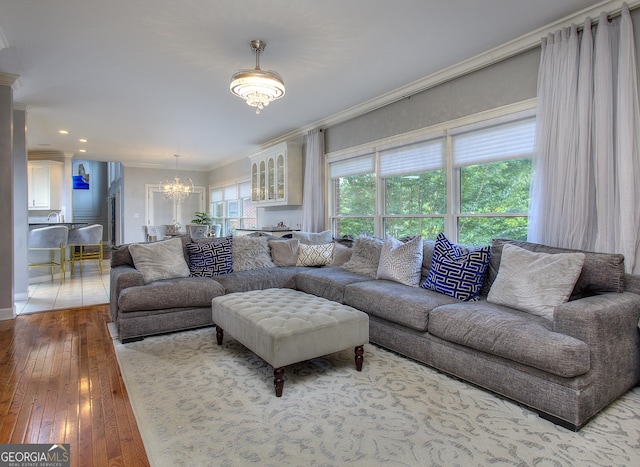 living room featuring hardwood / wood-style flooring, crown molding, and a notable chandelier