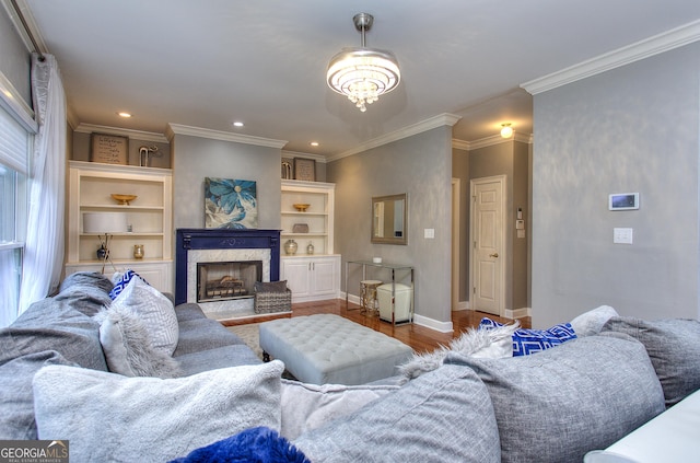 living room featuring a premium fireplace, ornamental molding, built in features, and light hardwood / wood-style flooring