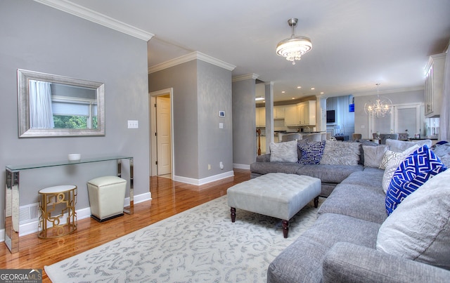 living room with ornamental molding, light hardwood / wood-style flooring, and a notable chandelier