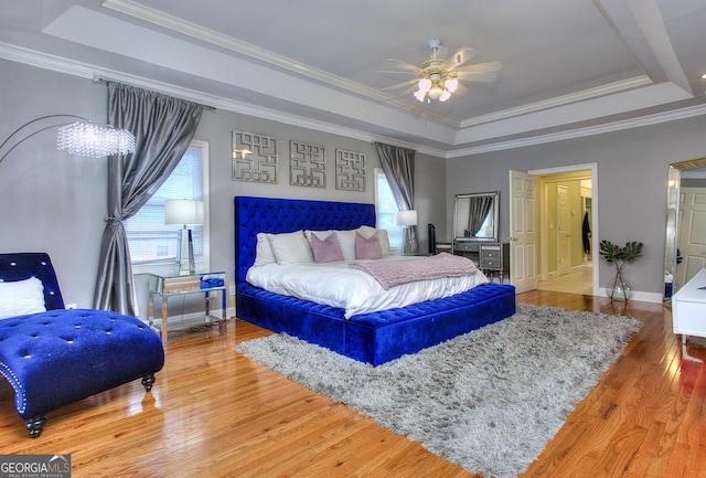 bedroom featuring ceiling fan, ornamental molding, a raised ceiling, and multiple windows