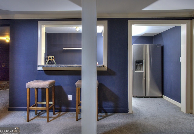 basement with stainless steel fridge with ice dispenser, crown molding, and carpet floors