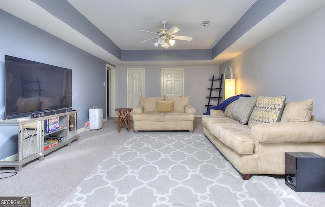 carpeted living room featuring a raised ceiling and ceiling fan