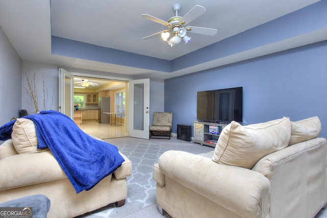 carpeted bedroom featuring stainless steel fridge, ceiling fan, and a tray ceiling