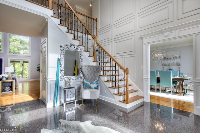 stairs featuring a high ceiling, ornamental molding, and a notable chandelier