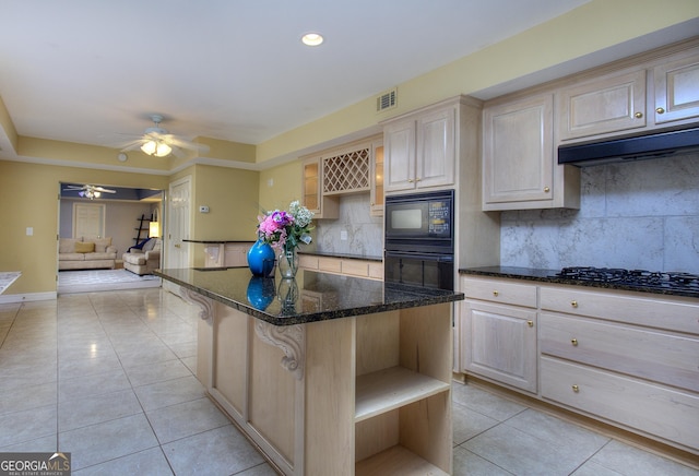 kitchen featuring a breakfast bar, tasteful backsplash, a center island, dark stone countertops, and black appliances