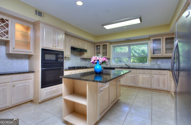 kitchen featuring a kitchen island, appliances with stainless steel finishes, light tile patterned floors, and dark stone counters