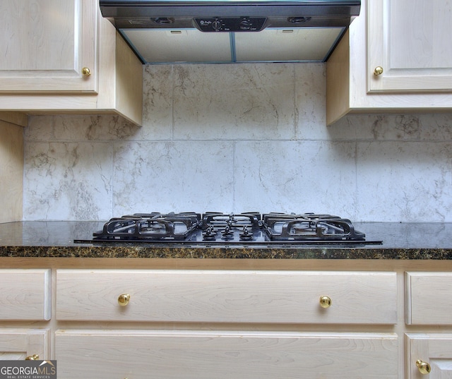 kitchen featuring decorative backsplash, range hood, dark stone counters, and black gas cooktop