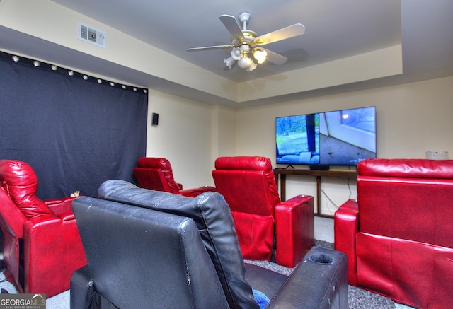 home theater with a raised ceiling, ceiling fan, and carpet flooring