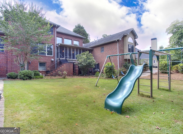 view of playground featuring a sunroom and a lawn