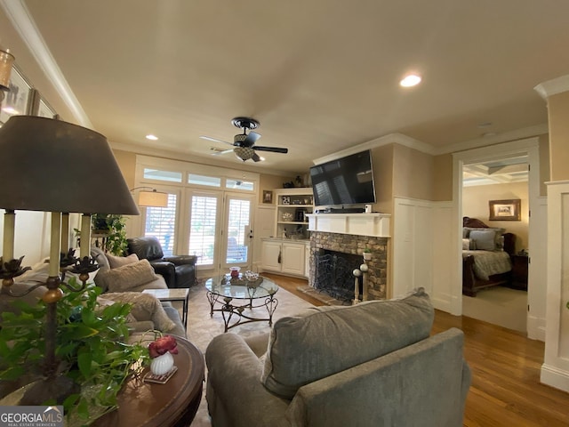 living room with ornamental molding, ceiling fan, a fireplace, and light hardwood / wood-style flooring