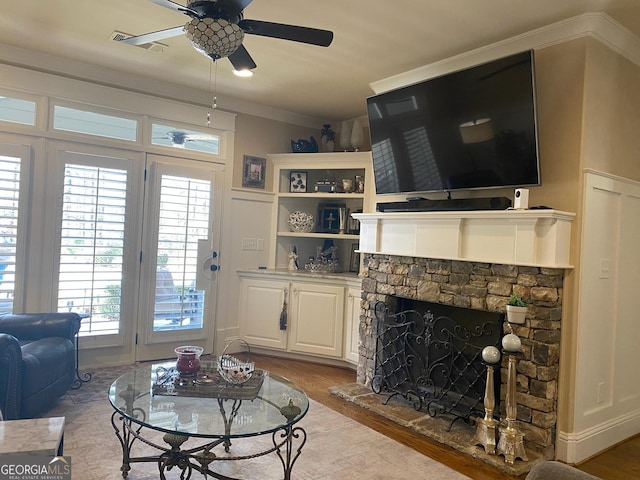 living room with ceiling fan, ornamental molding, a fireplace, and light hardwood / wood-style flooring