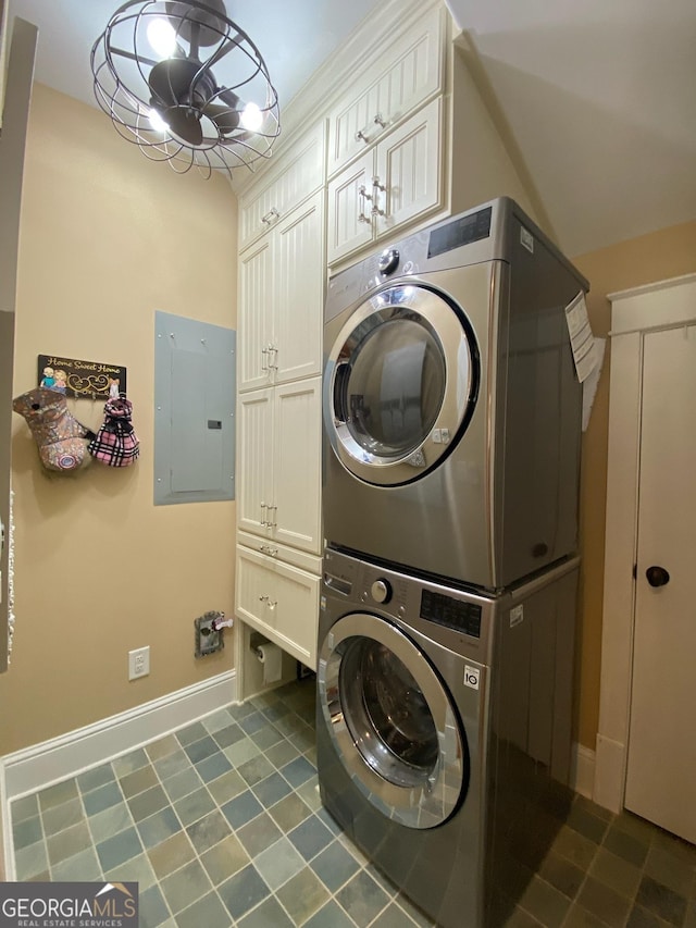 laundry room featuring electric panel, cabinets, and stacked washing maching and dryer