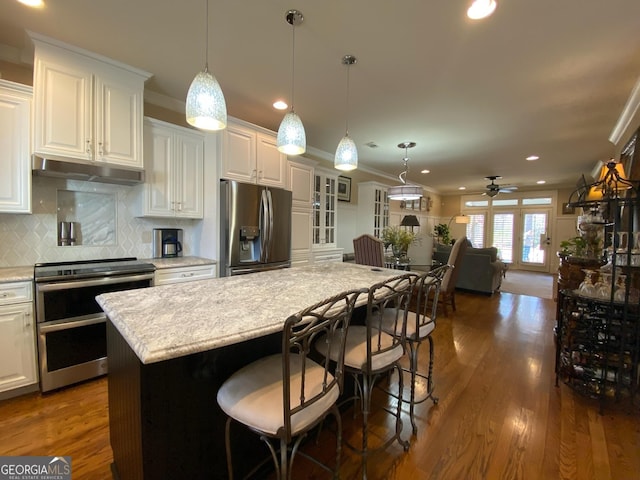 kitchen featuring pendant lighting, appliances with stainless steel finishes, a center island, white cabinets, and a kitchen bar