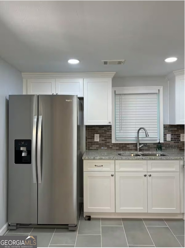 kitchen featuring white cabinetry, sink, stainless steel fridge, backsplash, and light stone countertops