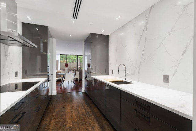 kitchen featuring floor to ceiling windows, light stone countertops, sink, and ventilation hood