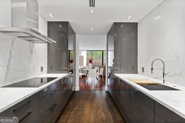 kitchen featuring island range hood, sink, black electric stovetop, floor to ceiling windows, and light stone countertops