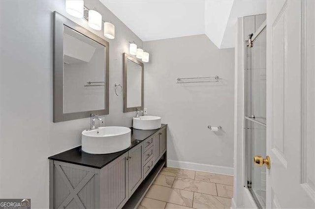 bathroom with an enclosed shower, a sink, baseboards, and double vanity