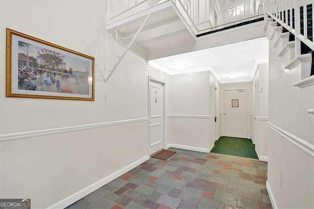 corridor with stone finish floor, baseboards, and ornamental molding