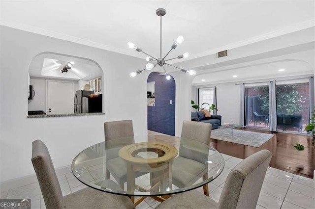 tiled dining area featuring arched walkways, visible vents, crown molding, and an inviting chandelier