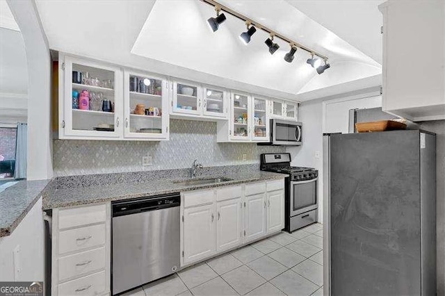 kitchen with appliances with stainless steel finishes, white cabinetry, a sink, light tile patterned flooring, and light stone countertops