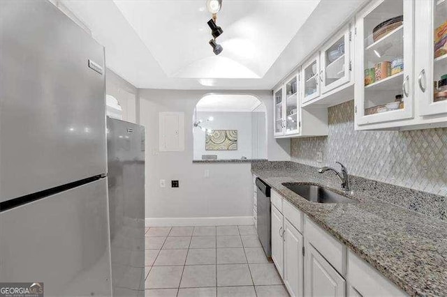 kitchen featuring a raised ceiling, appliances with stainless steel finishes, a sink, white cabinetry, and backsplash