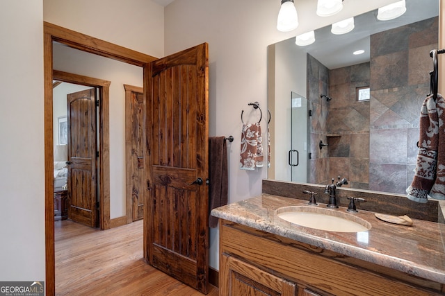 bathroom with a shower with door, wood-type flooring, and vanity