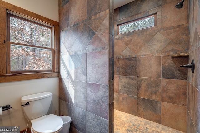 bathroom featuring plenty of natural light, a tile shower, and toilet