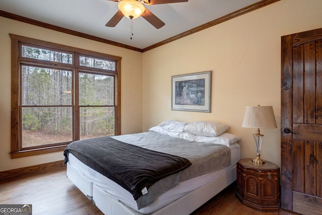 bedroom featuring wood-type flooring, crown molding, and ceiling fan