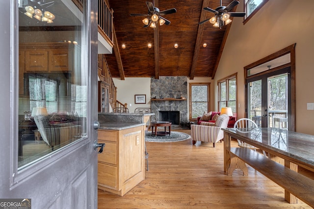 kitchen with wood ceiling, high vaulted ceiling, a fireplace, beamed ceiling, and light wood-type flooring