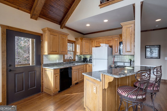 kitchen featuring a breakfast bar, dishwasher, sink, dark stone counters, and white refrigerator