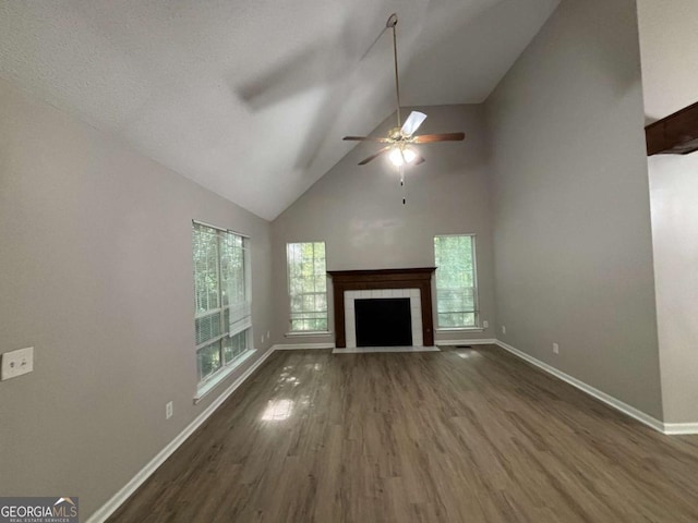 unfurnished living room with dark hardwood / wood-style flooring, high vaulted ceiling, ceiling fan, and a fireplace