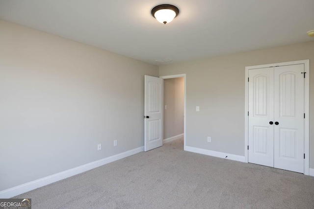 unfurnished bedroom featuring light colored carpet and a closet