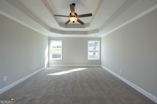 carpeted empty room with a raised ceiling, crown molding, and ceiling fan