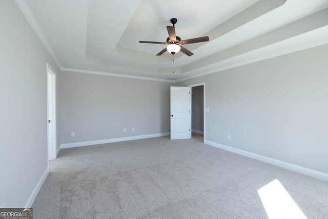 carpeted empty room with ornamental molding, a raised ceiling, and ceiling fan