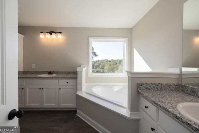 bathroom with vanity, a washtub, wood-type flooring, and lofted ceiling