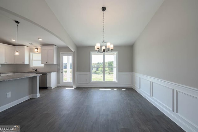 kitchen featuring dark wood-type flooring, white cabinets, light stone counters, and decorative light fixtures