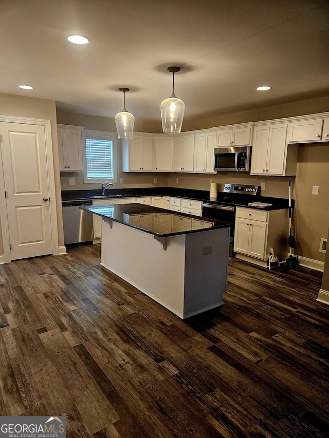 kitchen featuring a kitchen island, decorative light fixtures, white cabinetry, dark hardwood / wood-style flooring, and stainless steel appliances