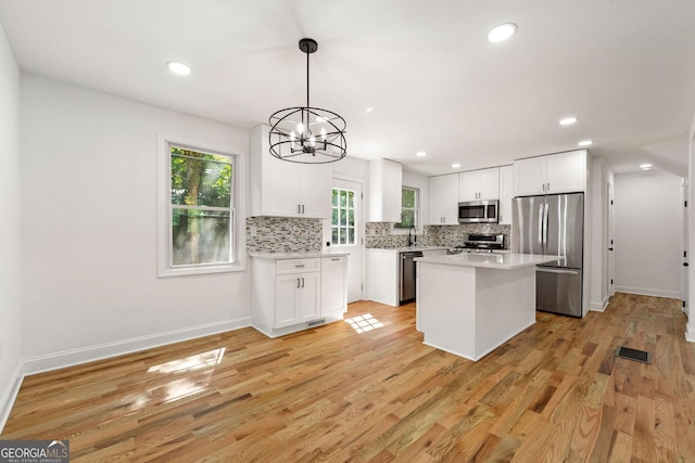 kitchen featuring pendant lighting, white cabinetry, a center island, light hardwood / wood-style floors, and stainless steel appliances