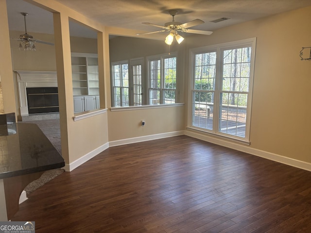 unfurnished room featuring ceiling fan, dark hardwood / wood-style flooring, and built in features